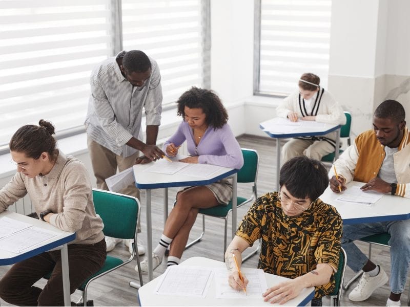 Schüler im ARISE Bildungswerk erlernen Softskills, während sie an Schreibtischen im Klassenzimmer sitzen.