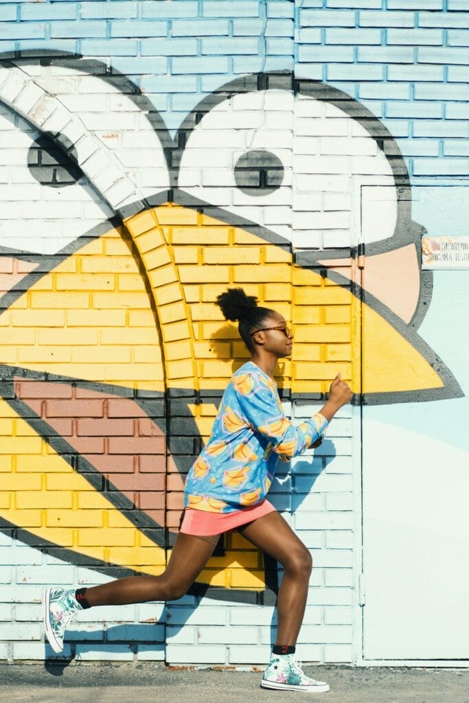 Dynamic scene of a woman running against a colorful graffiti wall, capturing urban art energy.